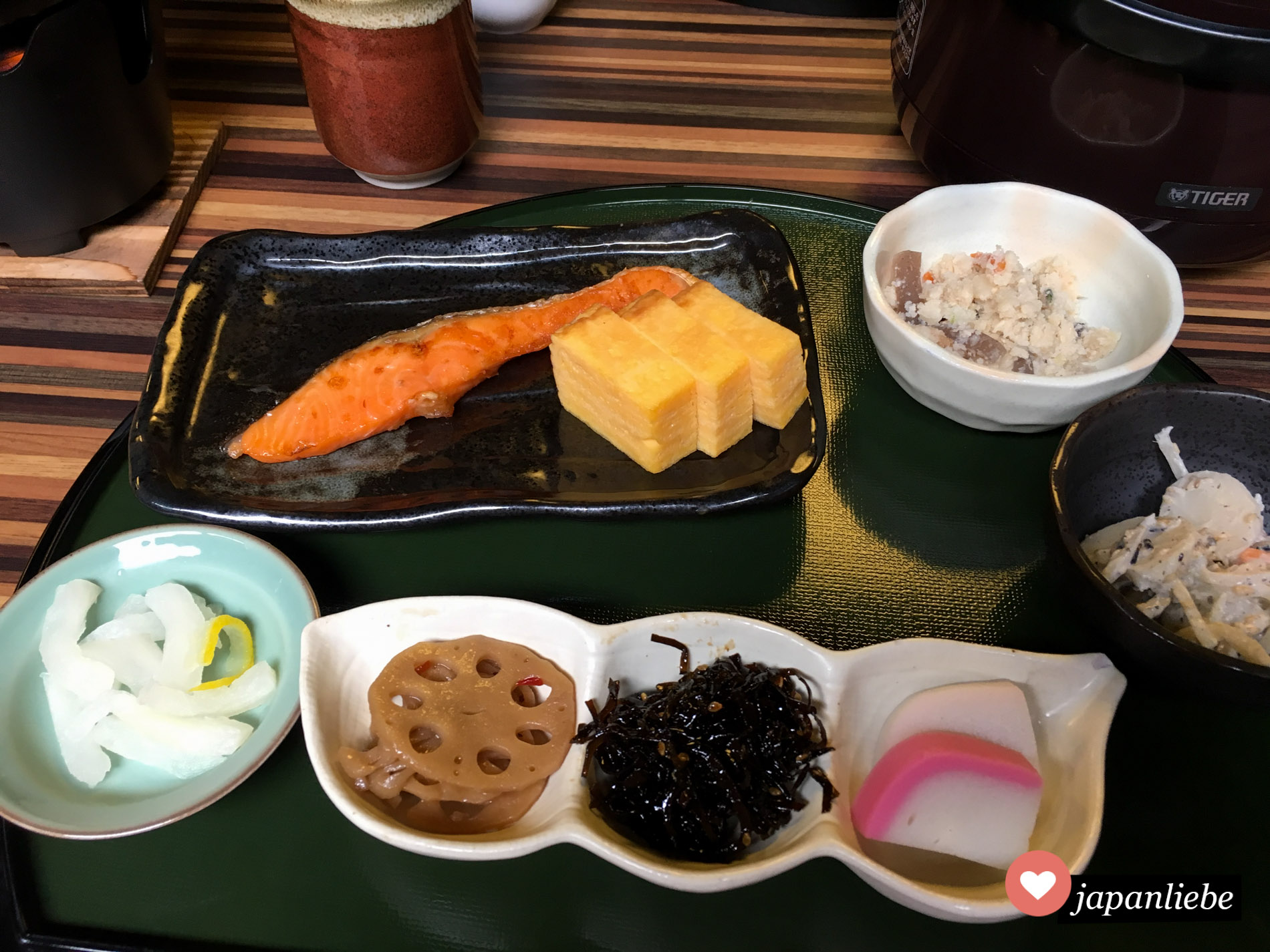 Bei diesem japanischen Frühstück sind viele traditionelle Zutaten vorhanden: Fisch, Ei, Lotuswurzel, hijiki-Algen, Rettich und japanische Salate.