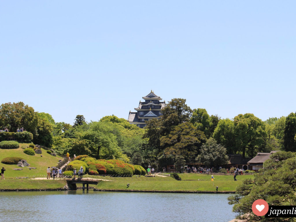 Der Koraku-en Garten In Okayama mit schwarzer Burg im Hintergrund.