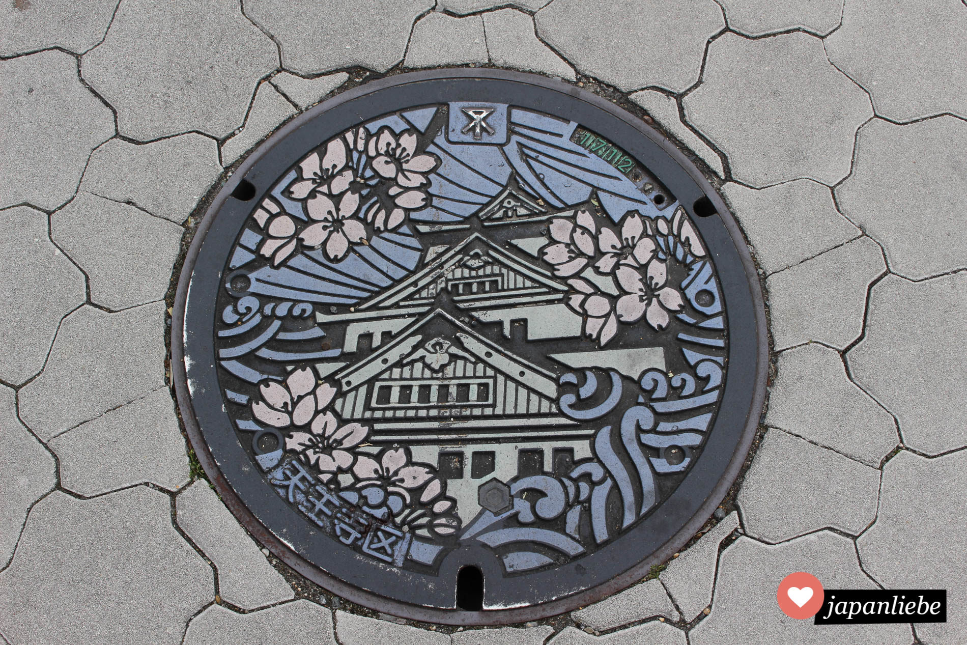 Ein besonders hübscher Kanaldeckel in Ōsaka zeigt Burg und Kirschblüten in Farbe.