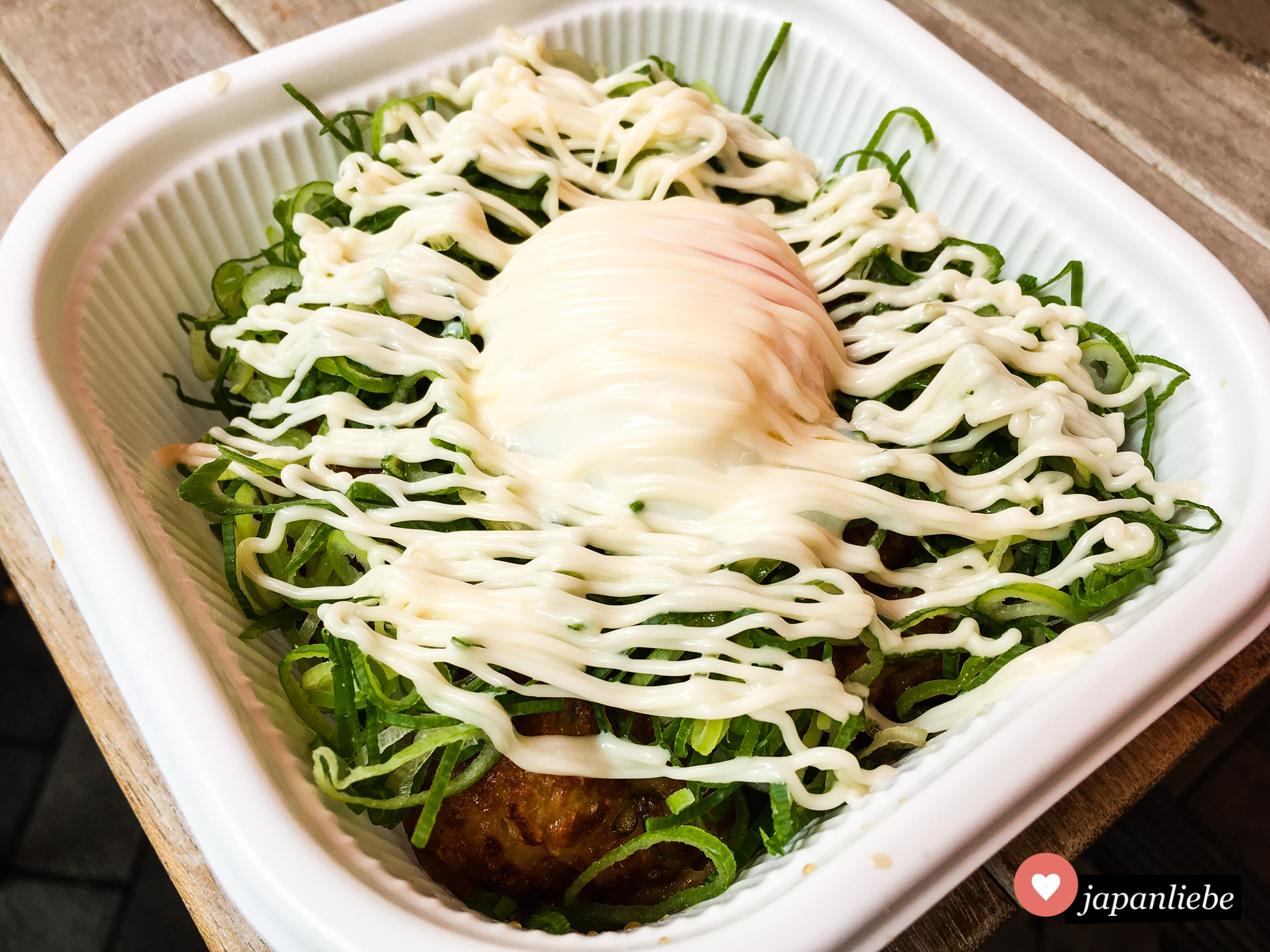 Eine takoyaki-Variation, die man in der Dōtonbori bekommt, sind takoyaki Oktopus-Teigbällchen mit einer dicken Schicht Frühlingszwiebeln, Mayo und einem wachsweichen Onsen-Ei.