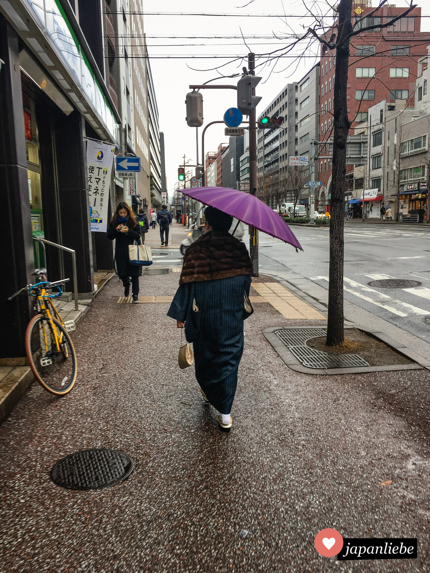 An einem regnerischen Tag in Kyōto ist eine Frau mit Kimono und Regenschirm unterwegs.