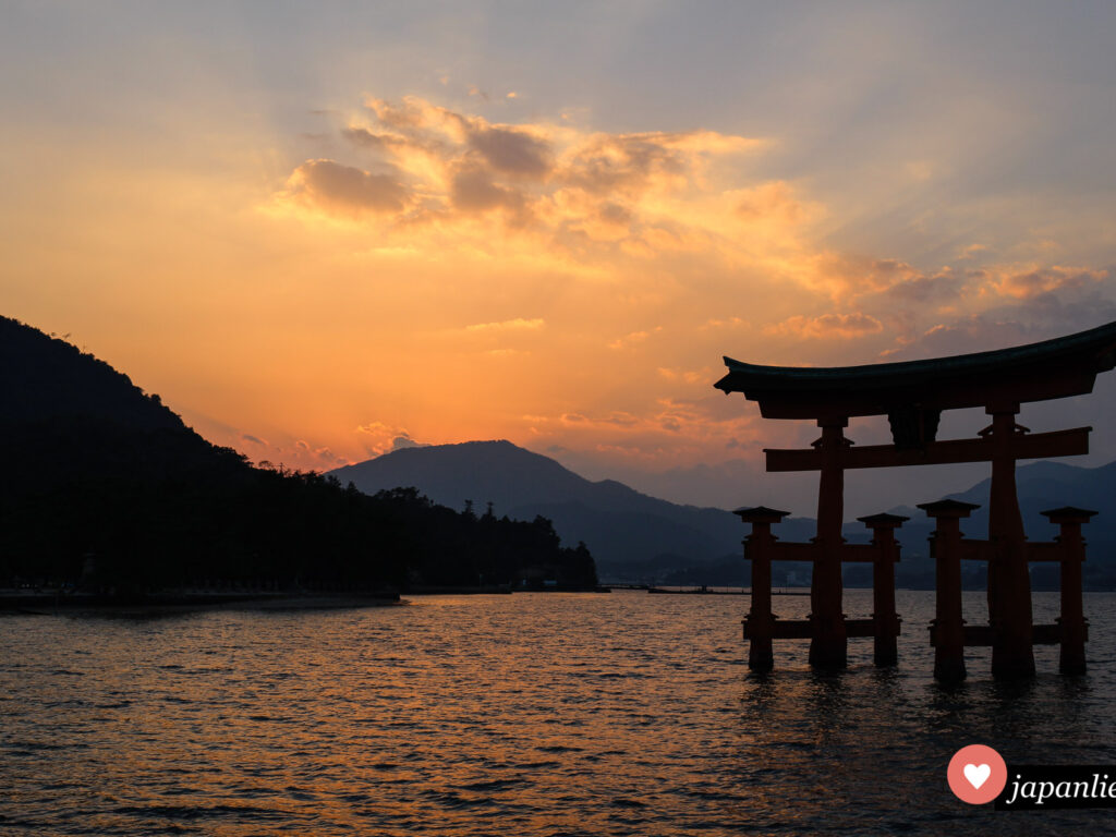 Das berühmte Schreintor des Itsukushima-Schreins auf der heiligen Insel Miyajima vor der Küste Hiroshimas bei Sonnenuntergang und Flut.
