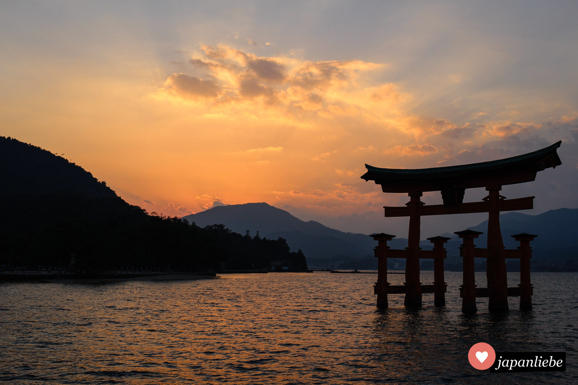 Das berühmte Schreintor des Itsukushima-Schreins auf der heiligen Insel Miyajima vor der Küste Hiroshimas bei Sonnenuntergang und Flut.