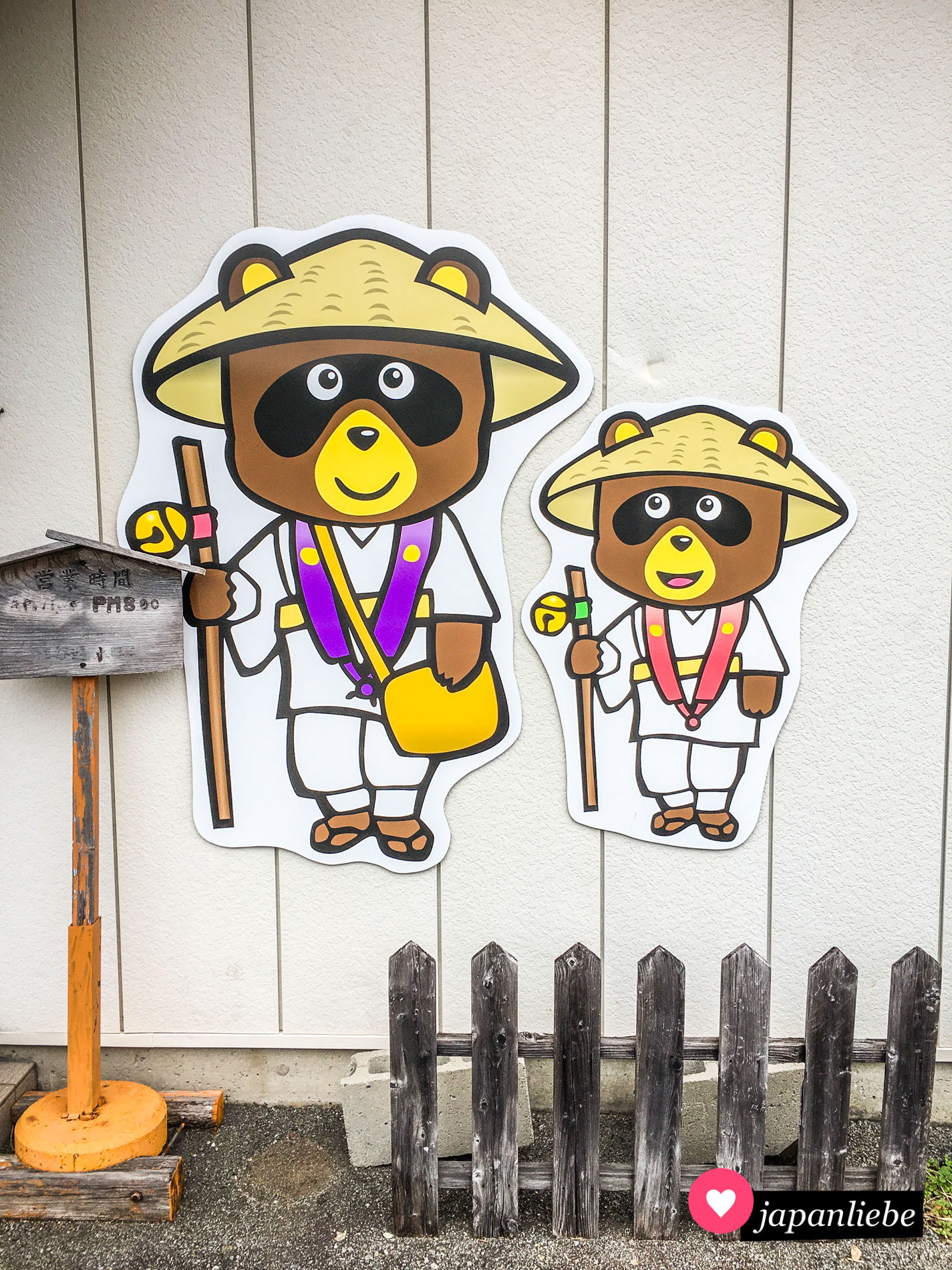 Zwei Comic-Tanuki im typischen Pilgergewand der 88-Tempel-Wallfahrt auf Shikoku.
