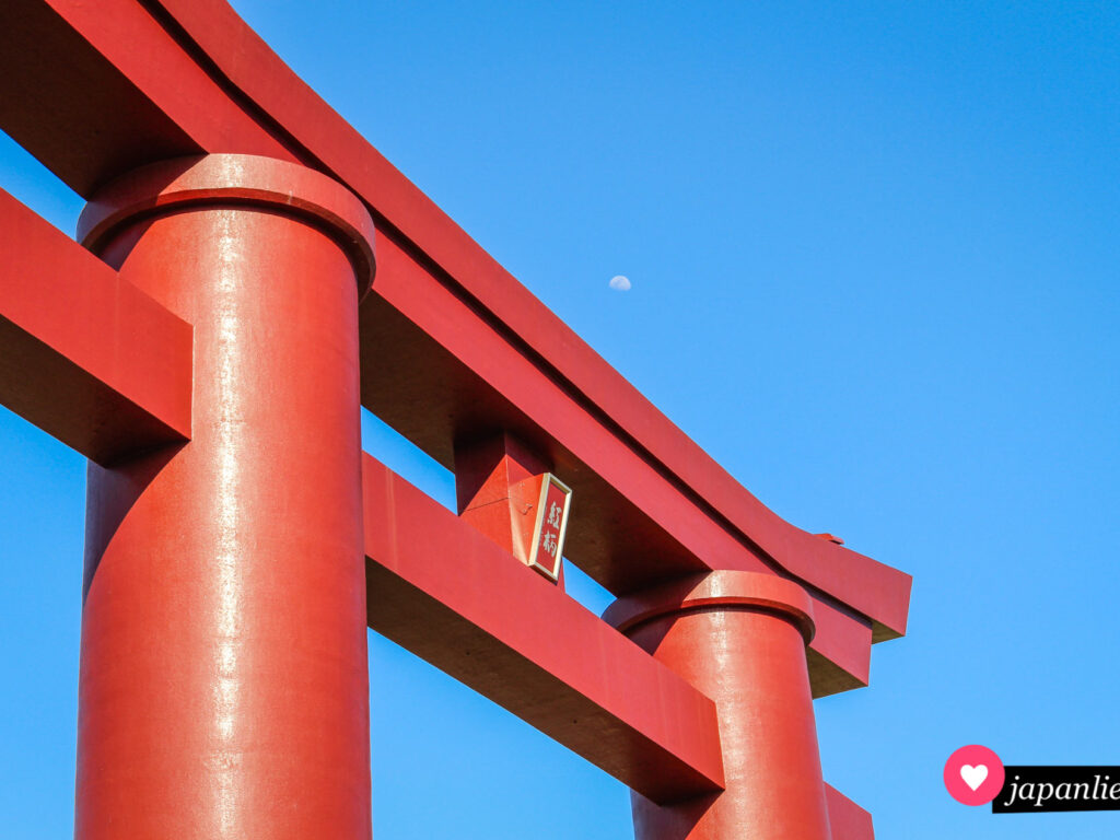 Das große, dunkelrote Schreintor des Saijo Inari mit dem Mond im Hintergrund.