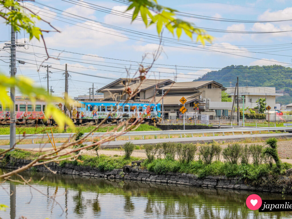 Ein Zug im Momotarō-Design fährt über die Kibi-Ebene nahe Okayama.