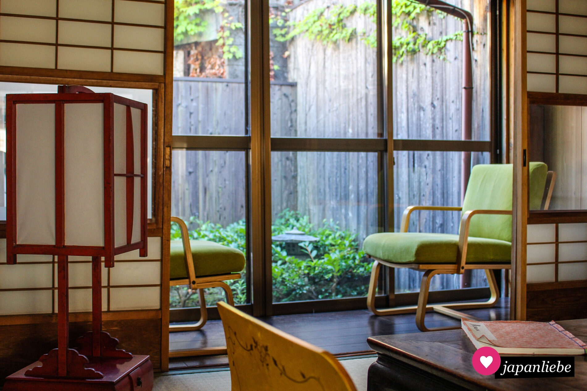 Das Ferienhaus „Koyasu“ in Kyōto hat einen kleinen Wintergarten mit Blick nach draußen auf eine Steinlaterne.