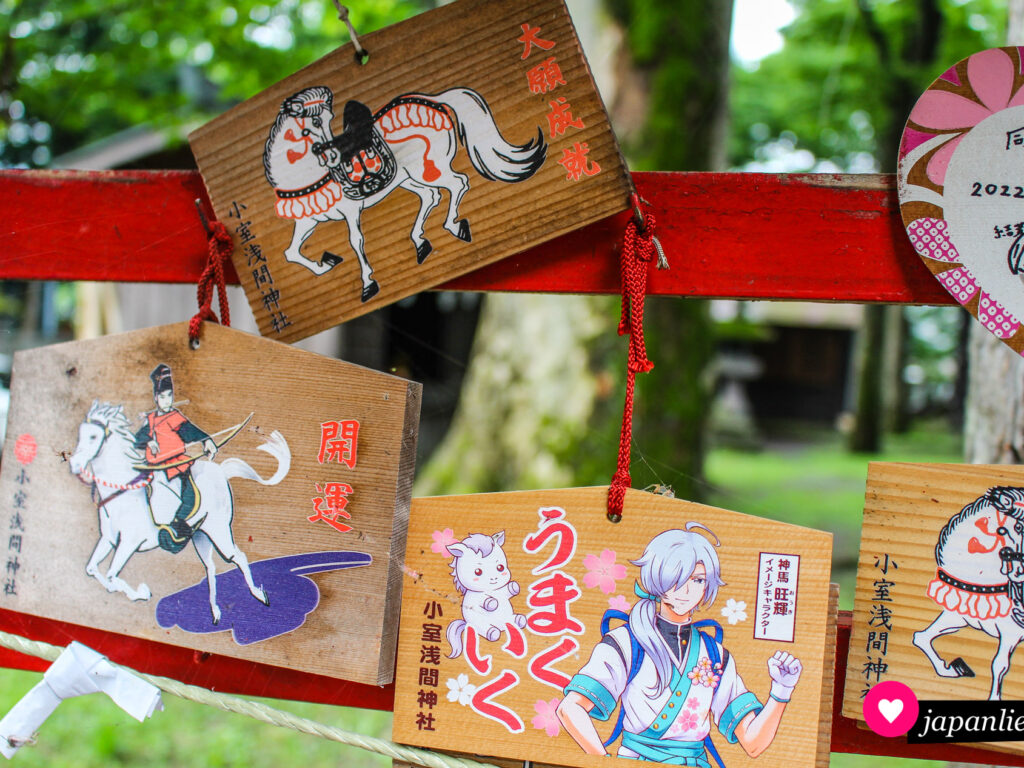 Am Fujisan Shimomiya Omuro Sengen-Schrein in Fujiyoshida gibt es gleich mehrere „ema“-Wunschtafeln mit Pferdemotiven. Eins davon inklusive Animefigur und Wortspiel. In „umaku iku“ = „wird gut gehen“ steckt zumindest bei der Aussprache das „uma“ von Pferd.