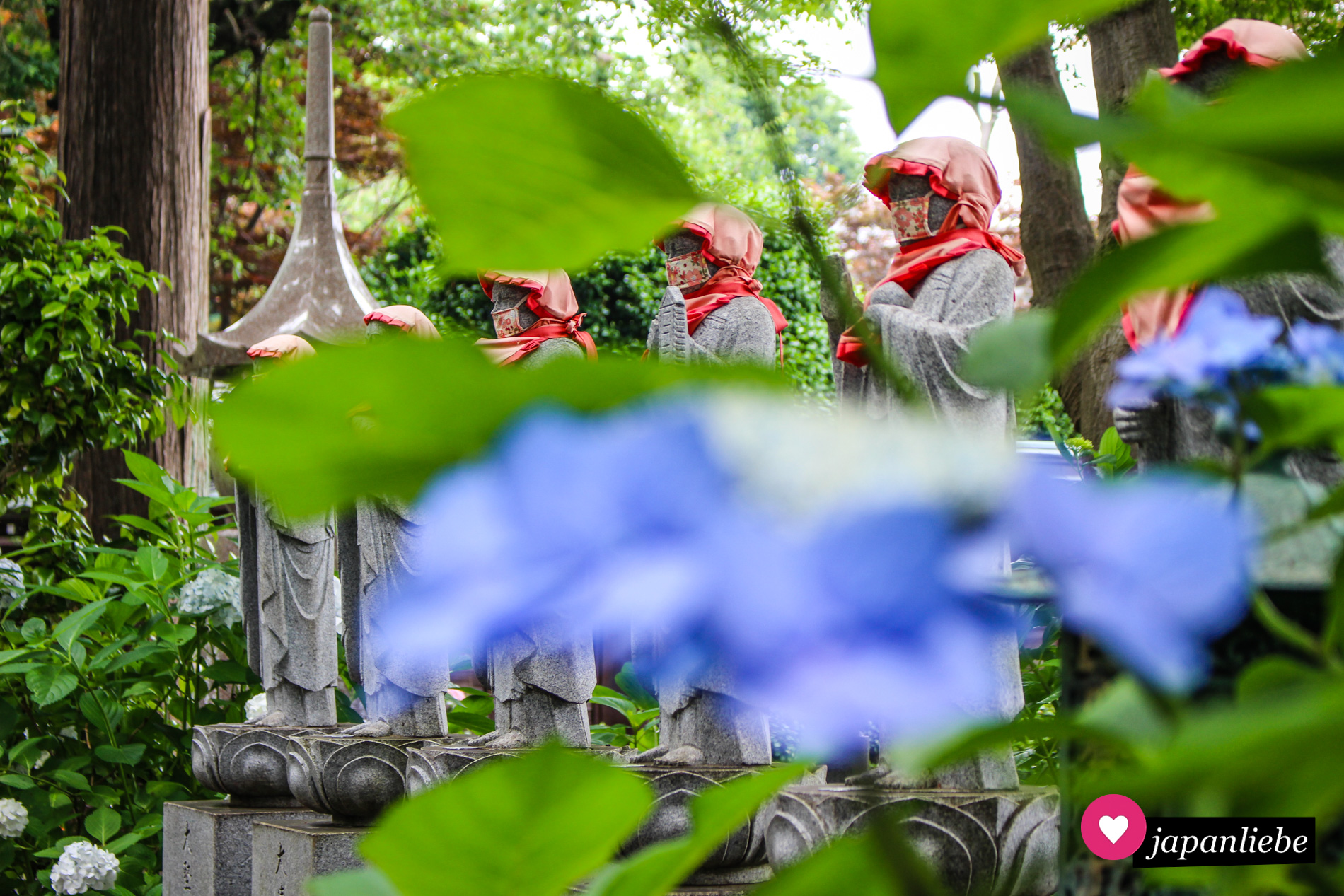 Eine Reihe Statuen entlang des Weges auf dem Gelände des Myōraku-ji-Tempels. An den Masken lässt sich erkennen, dass das Foto während der Pandemie entstand.