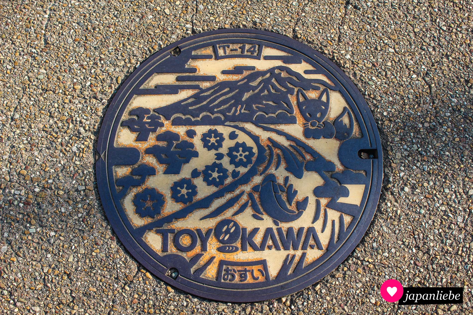 Dieser Kanaldeckel zeigt den Toyokawa-Fluss mit Fisch, einen Fuchs, den Hongū-Berg und die beiden Symbole der Stadt: Schwarzkiefer und Azaleen.