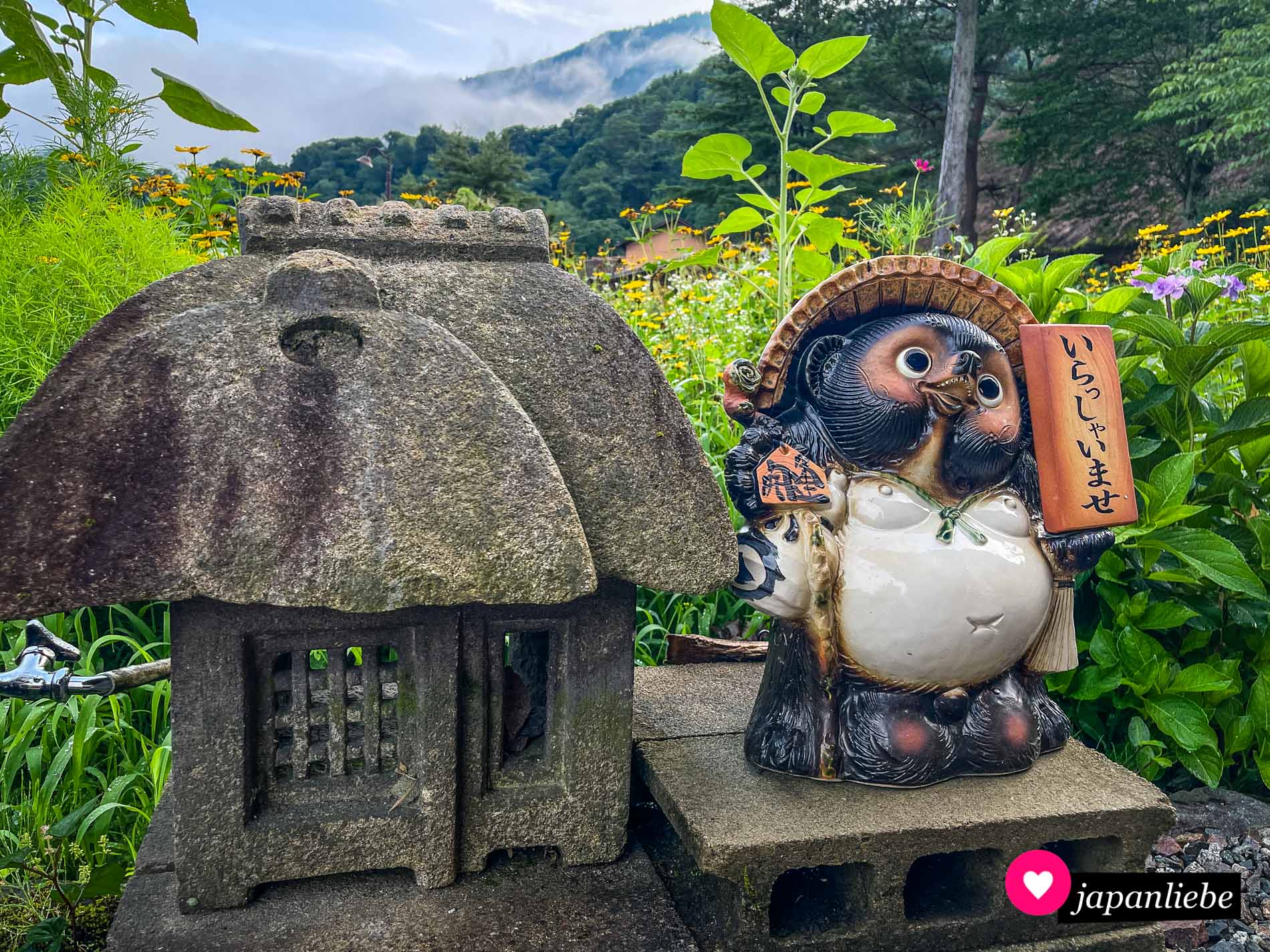 Eine Steinlaterne und ein Tanuki heißen die Besucher willkommen.