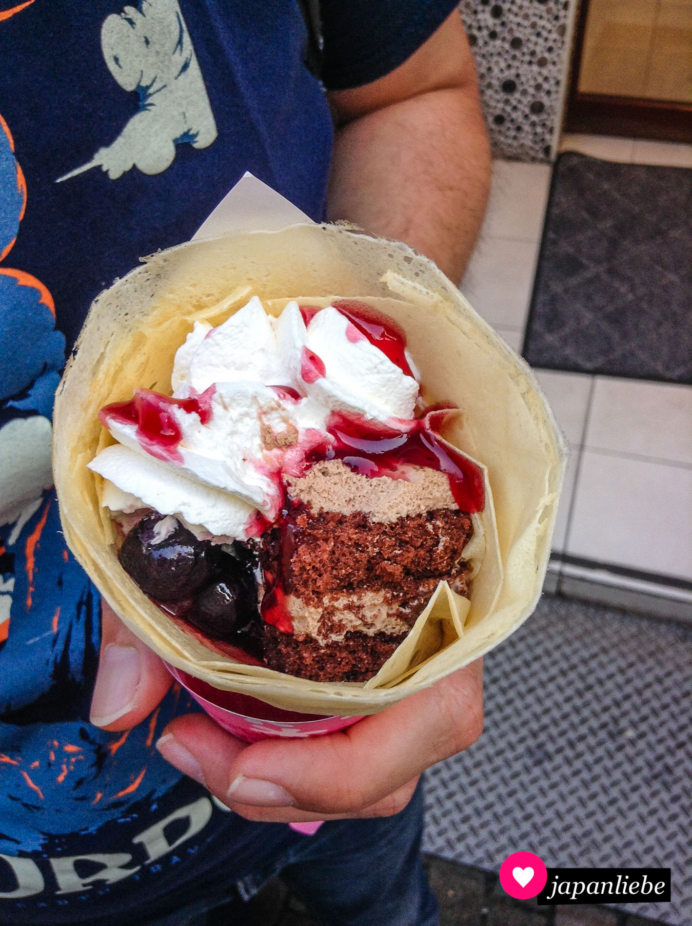 Ein Crêpe mit Schoko-Sahne-Torte-Stückchen und Kirschen.